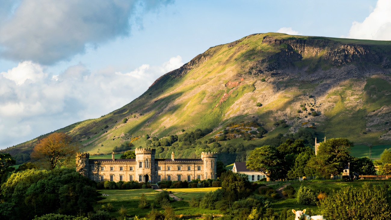 Dungiven Castle set in green fields below the slope of Benbradagh mountain, with sheep grazing