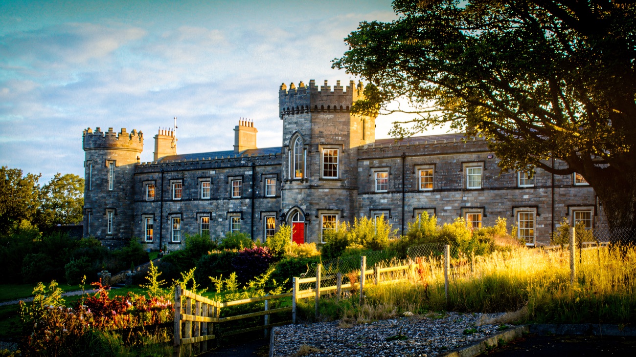 A warm evening view of Dungiven Castle's tower and red door framed by a large tree