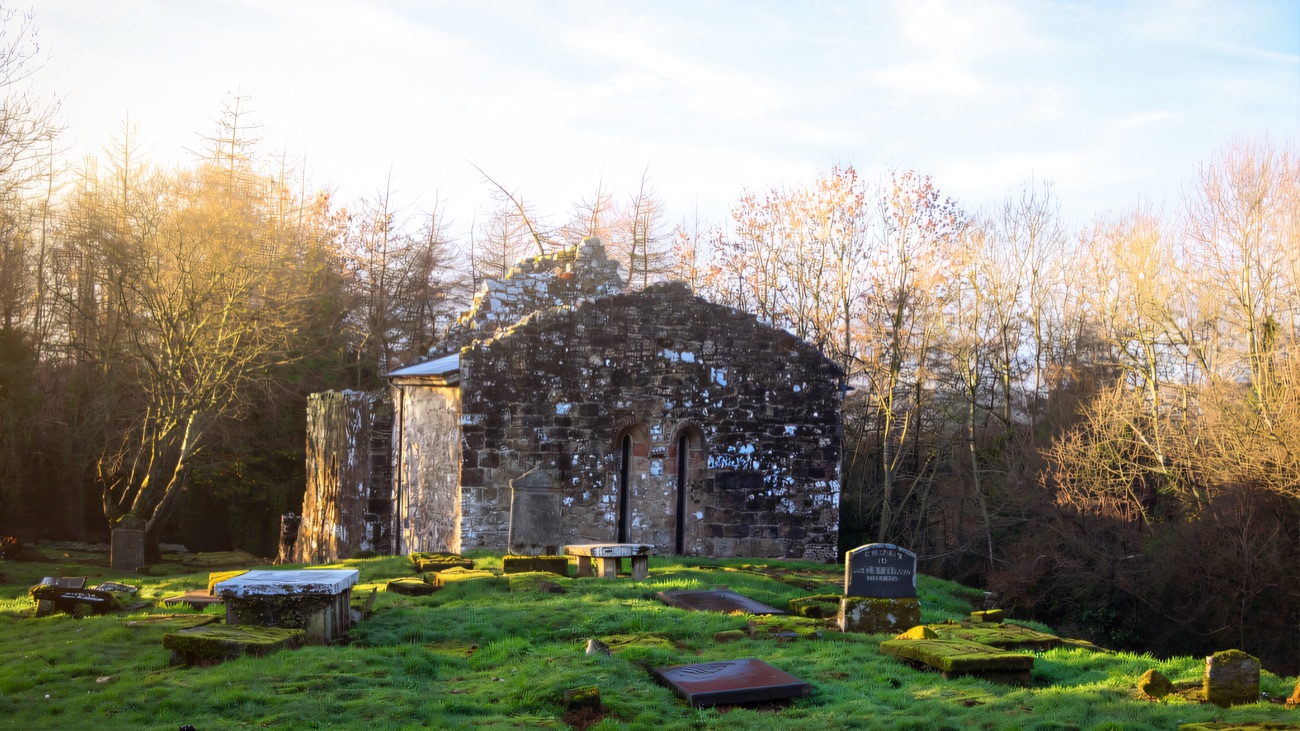 The priory ruin in its graveyard under soft winter light
