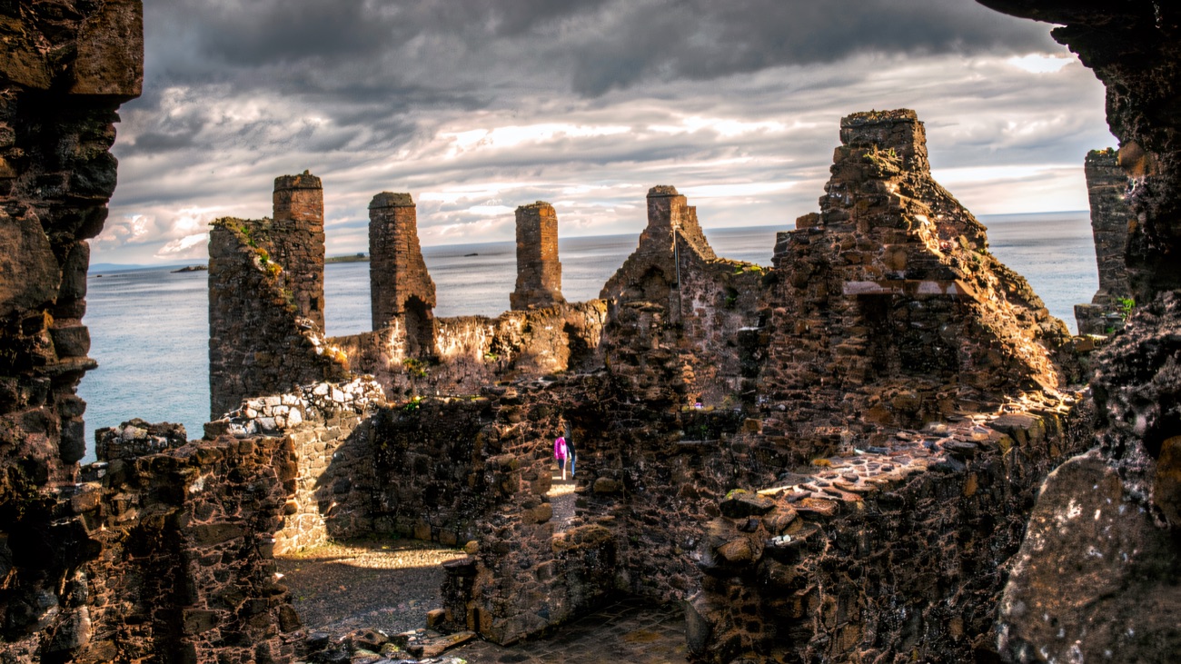 Inside the roofless ruins of Dunluce Castle, stone walls and chimney stacks against the sea