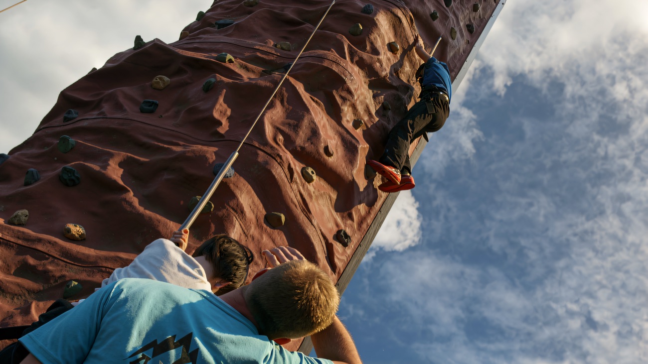An instructor belaying a climber on the outdoor climbing tower