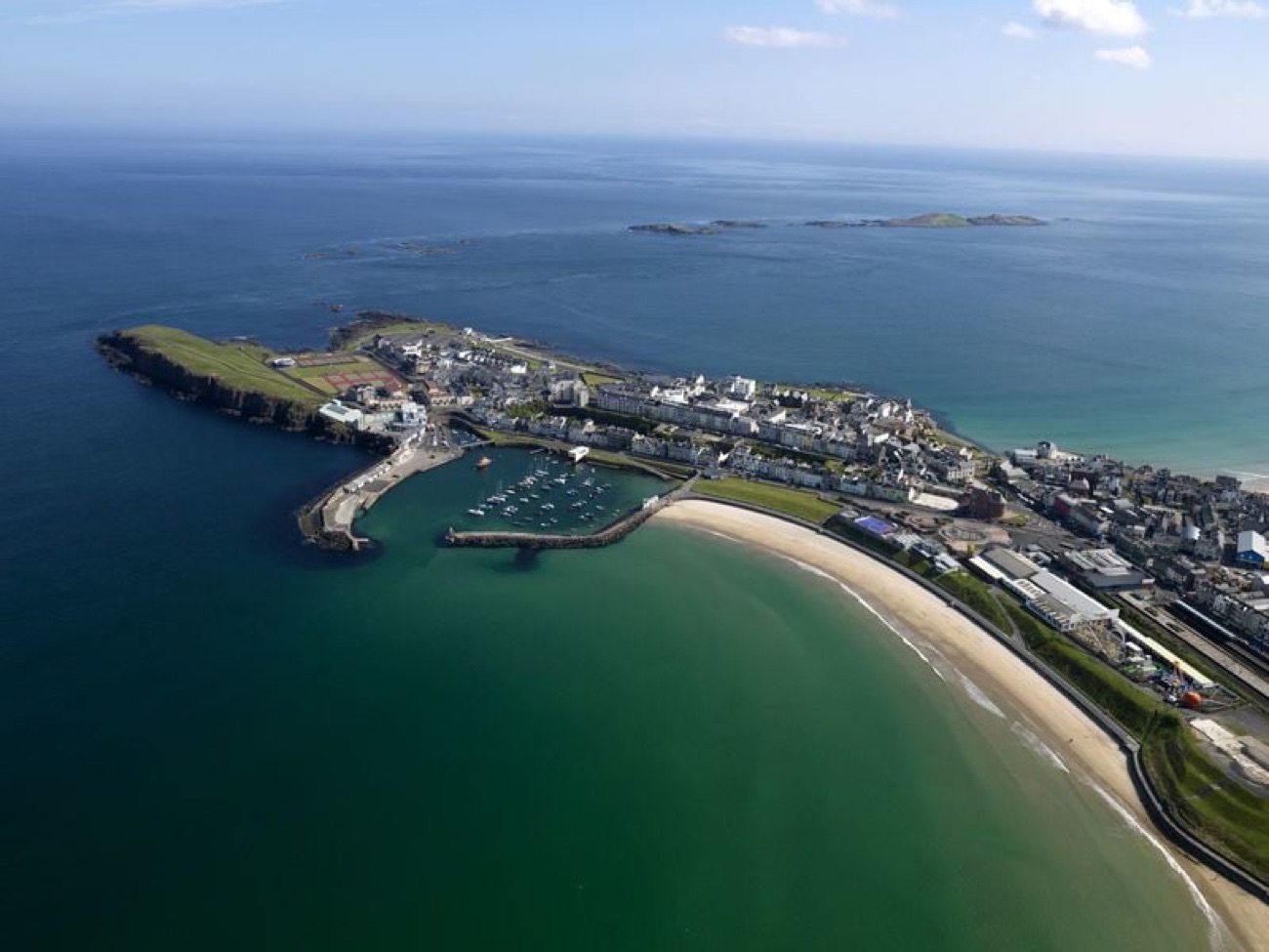 Aerial of the Portrush peninsula and harbour with East Strand sweeping away alongside the town