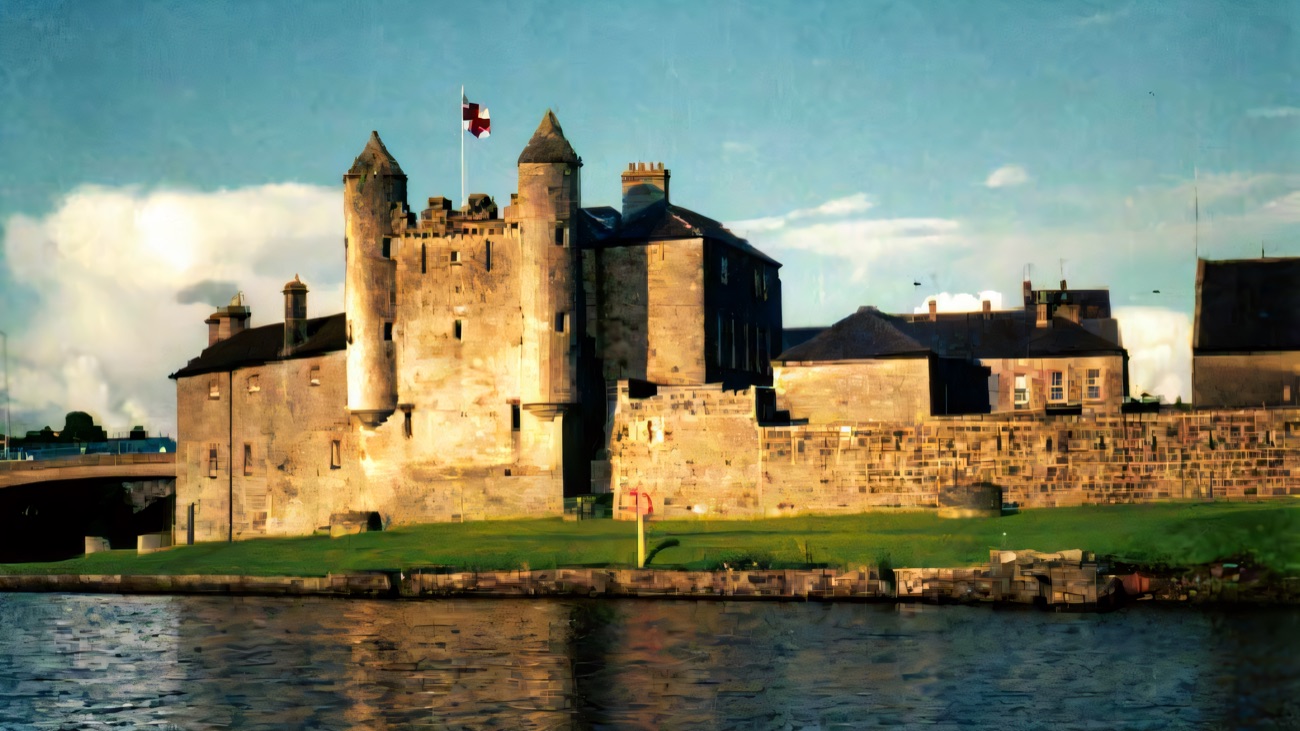 The keep and curtain walls of Enniskillen Castle seen from the water, its turreted tower rising above the barracks buildings