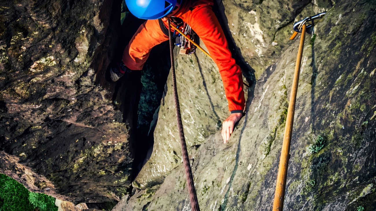 Looking down on a helmeted climber moving up a crack line in the rock