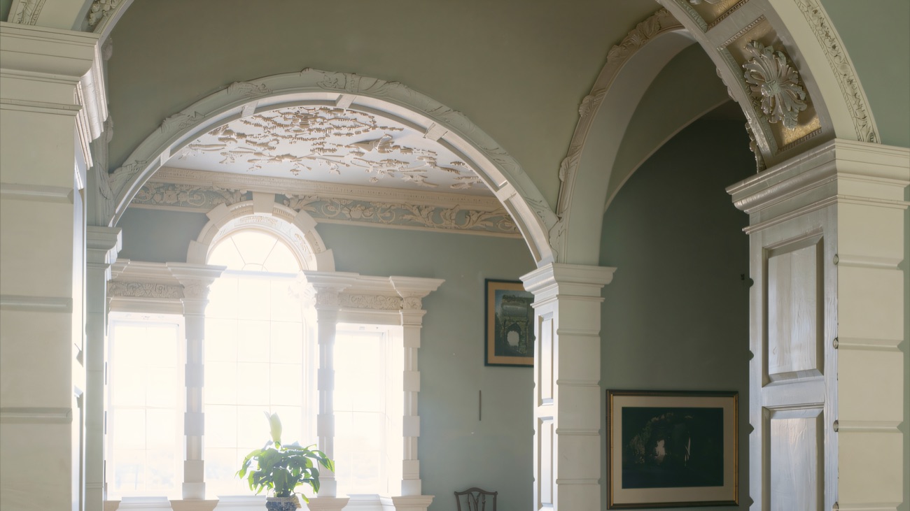 Ornate white rococo plasterwork arches and a decorated ceiling inside Florence Court