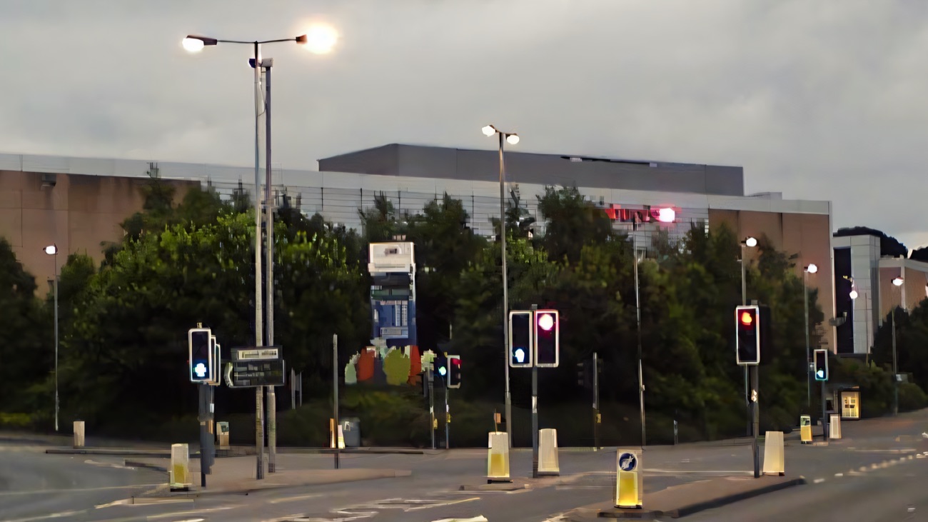 Forestside Shopping Centre seen from the road, a long low frontage with the Sainsbury's sign, at dusk