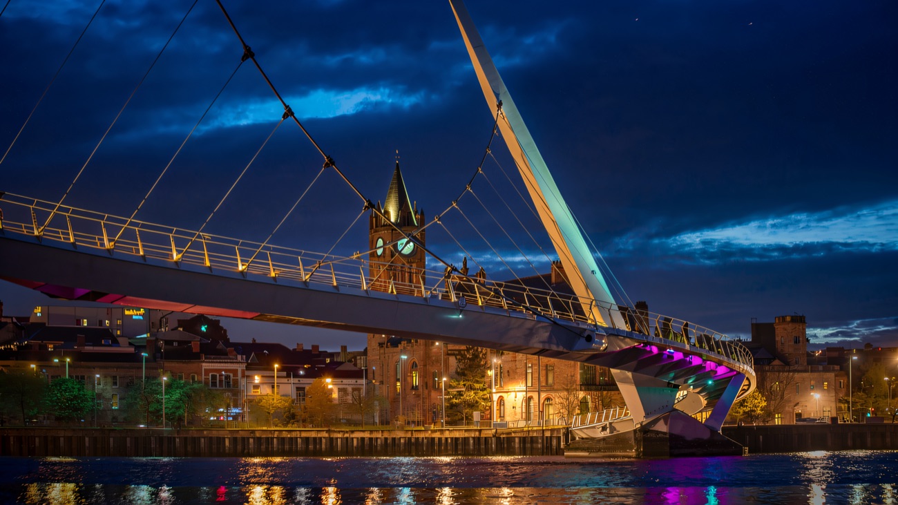 The Peace Bridge lit up over the river after dark.
