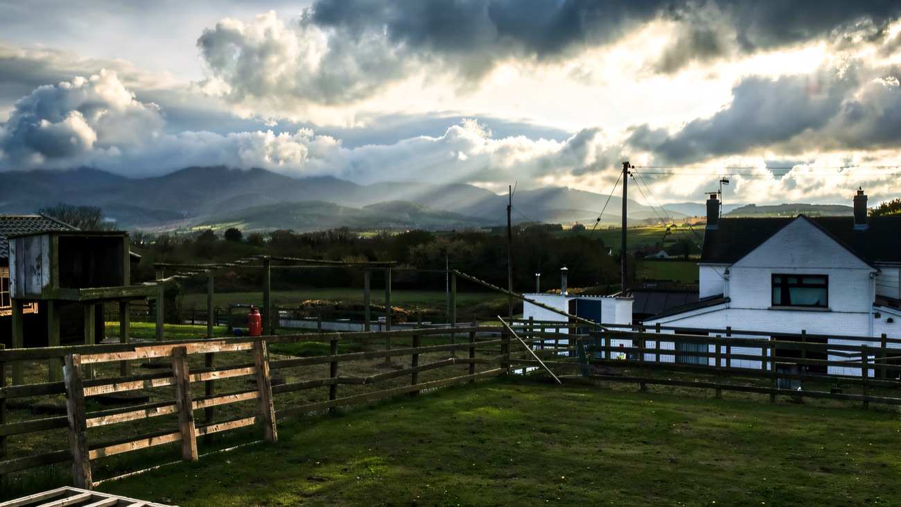 The farmhouse and animal pens at Funny Farm with the Mournes clouded over in the distance