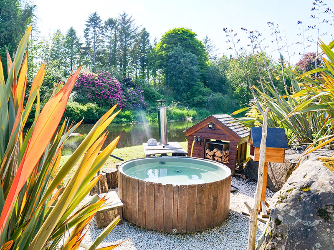 A wood-fired riverside bathing tub steaming beside the River Maine in the Thermal Spa Village