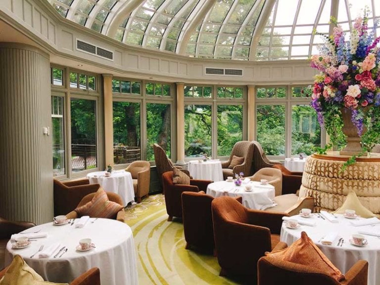 The bright glass-domed Conservatory dining room at Galgorm, set with white-linen tables