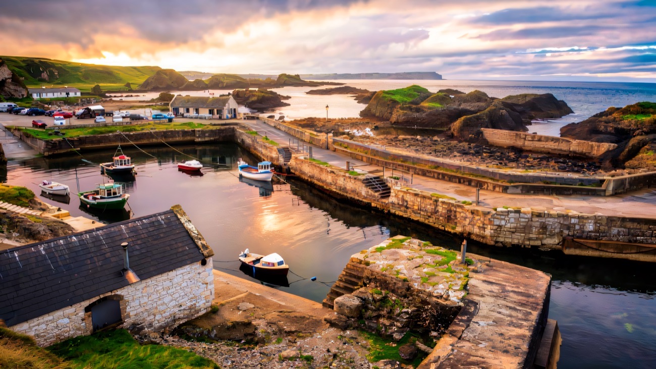 Ballintoy Harbour from above at sunset with boats moored between the stone quays