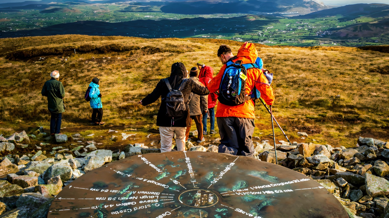 Walkers at a summit toposcope looking out over the Mourne landscape