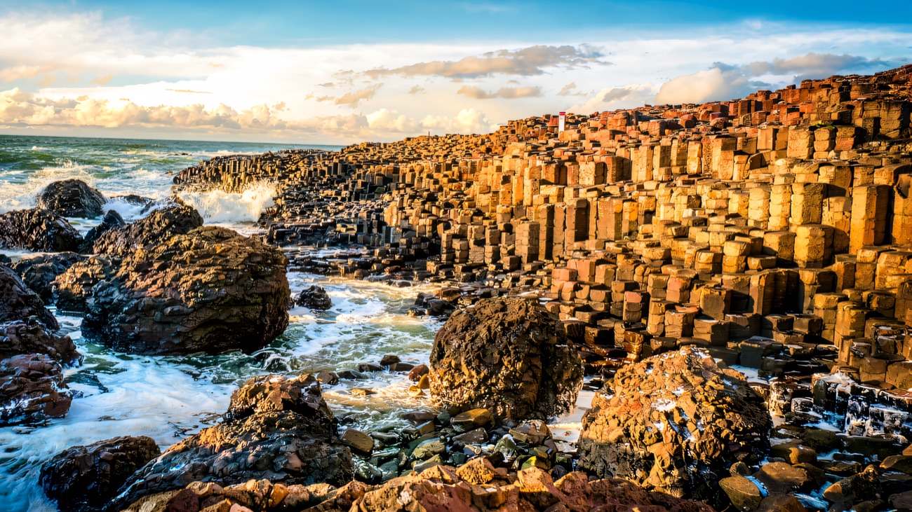 The basalt columns march down to the sea under a bright, breezy sky.