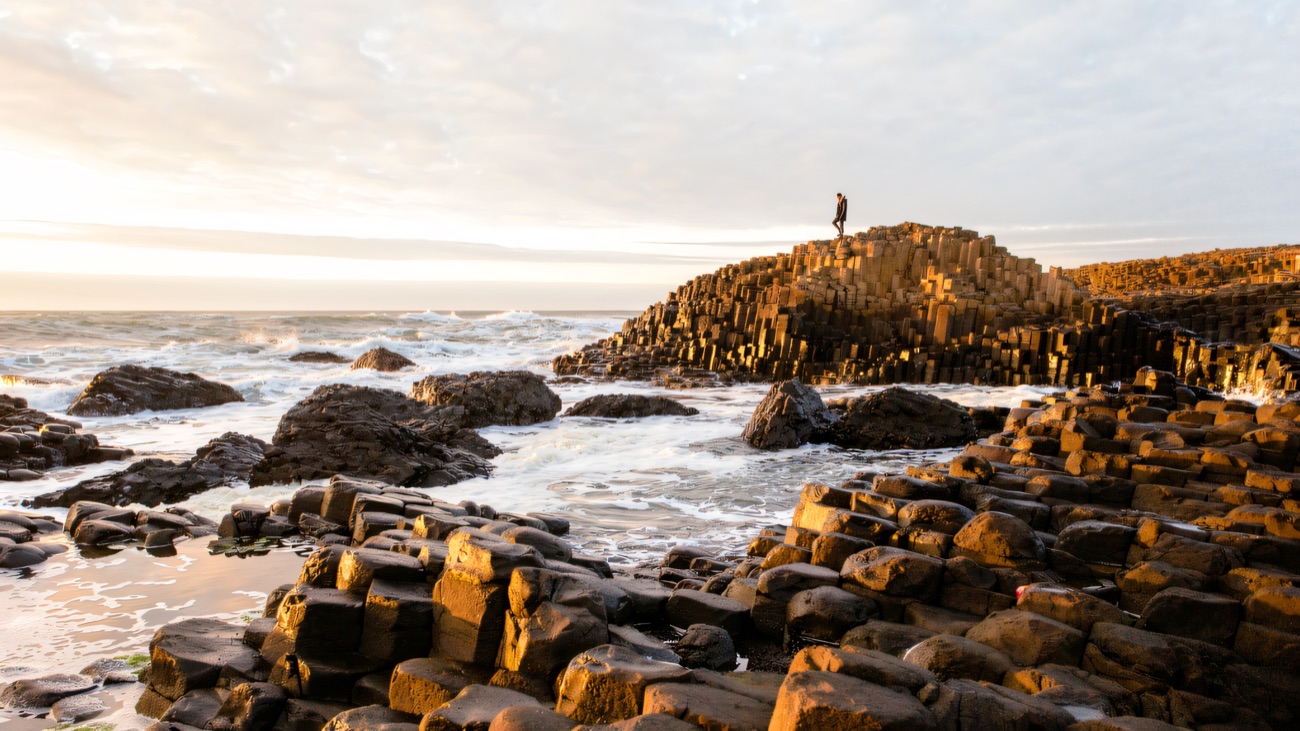 A lone figure stands on the columns as the last light gilds the stone.
