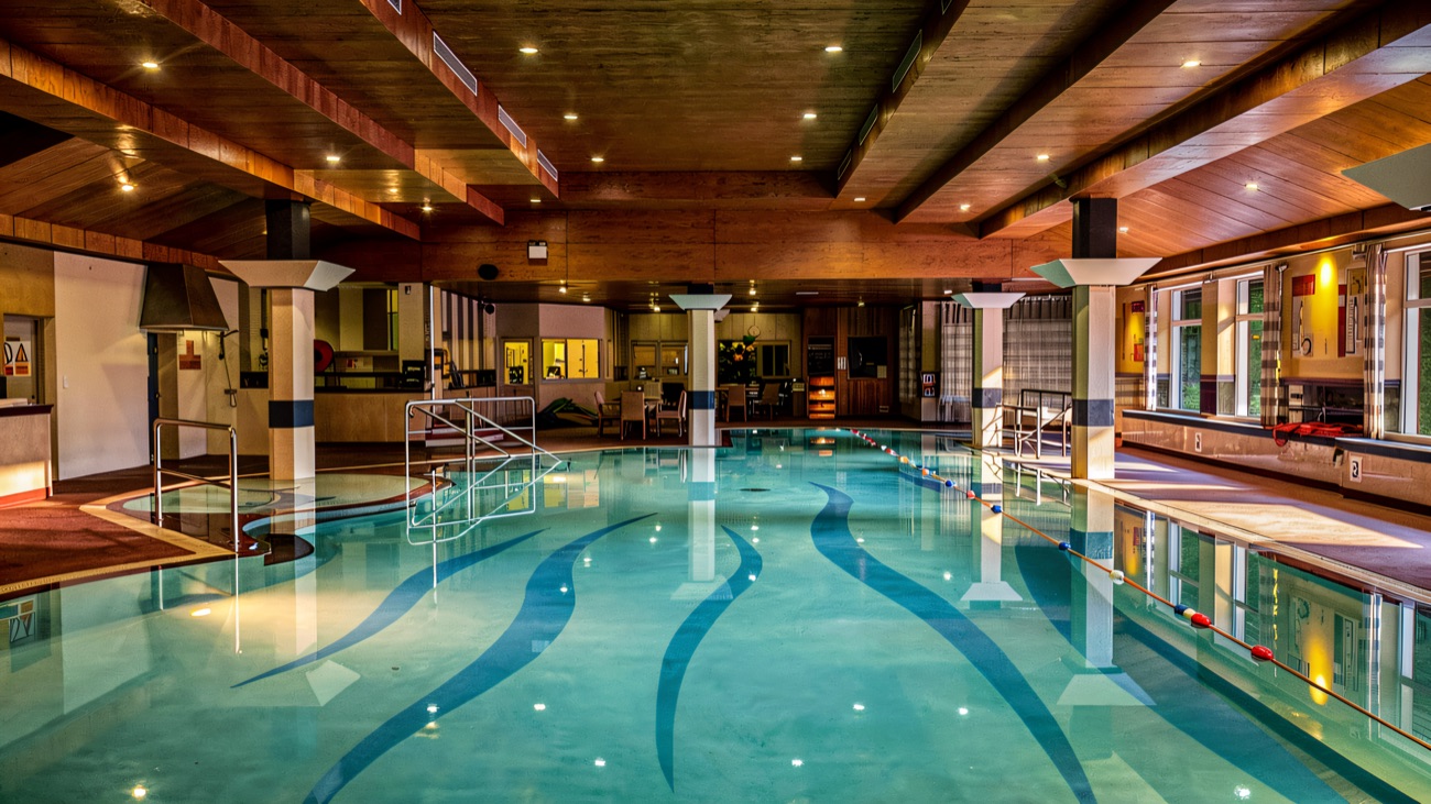 A wide view over the pool with a wooden ceiling and a lounge area beyond.