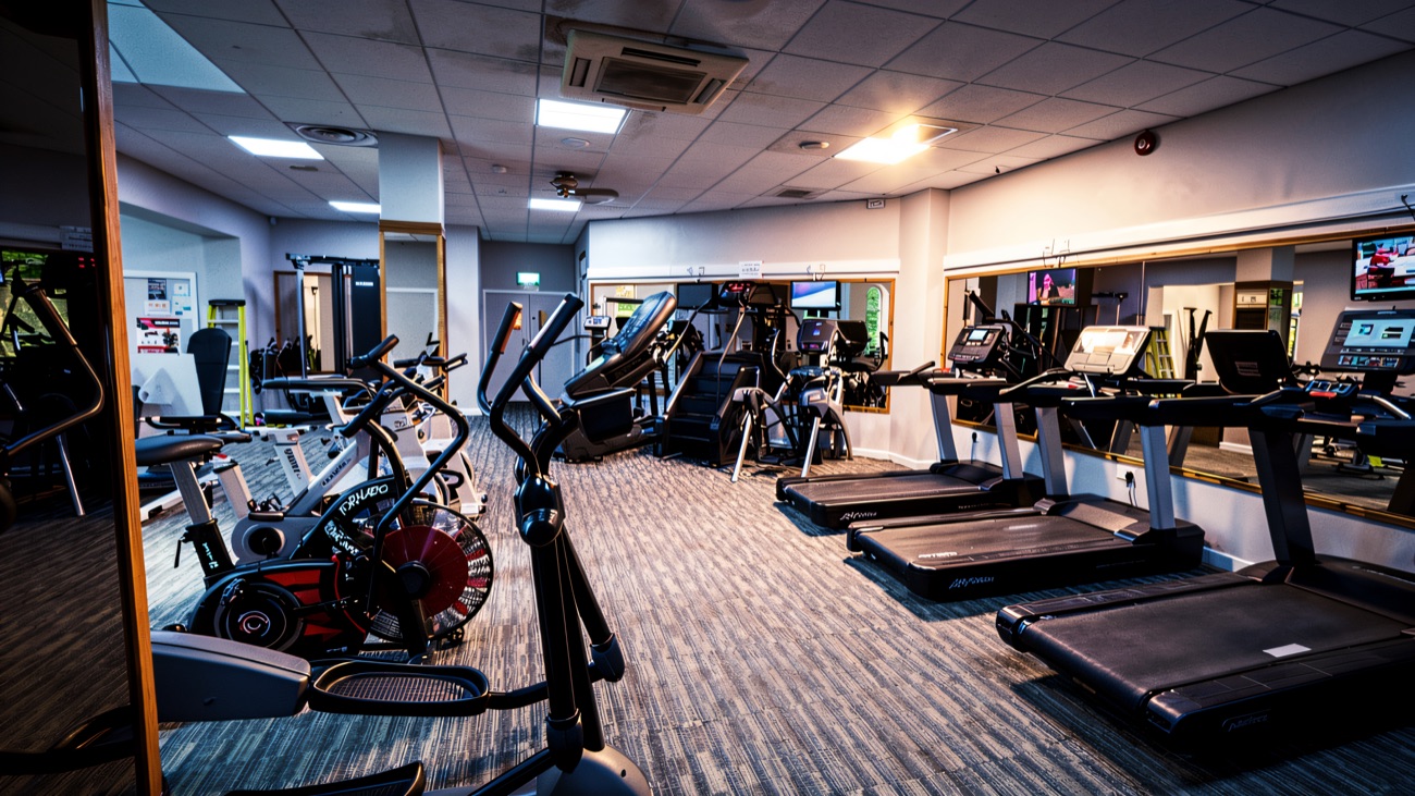 The gym, with a row of treadmills, cross-trainers and bikes facing the mirrors.