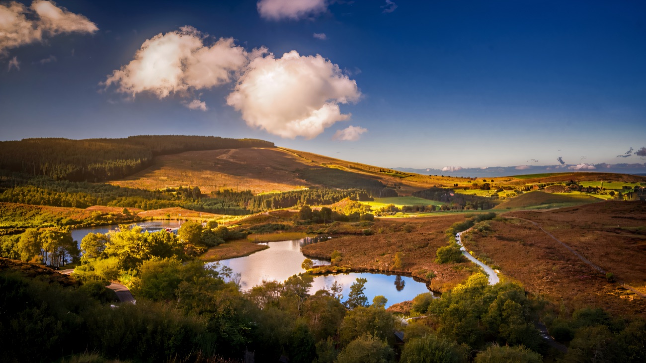 Sperrin scenery near Gortin — heather-covered hills, small loughs and forested slopes under a blue sky