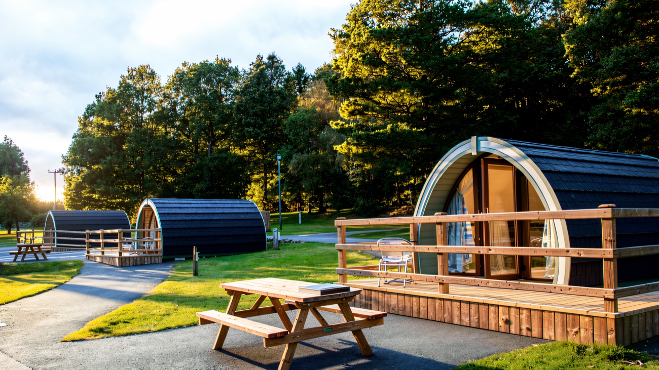 Camping pods with decking and a picnic bench beside the trees