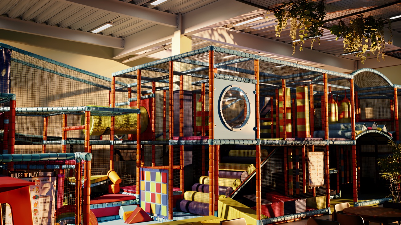 The two-tier netted play frame with slides, climbing steps and a porthole window, seen from the café tables