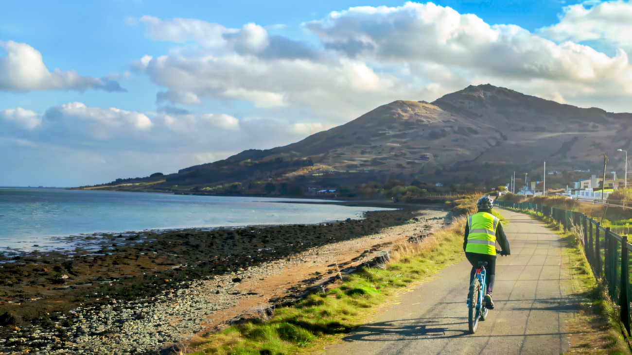 A cyclist on the lough-side trail beneath the mountains