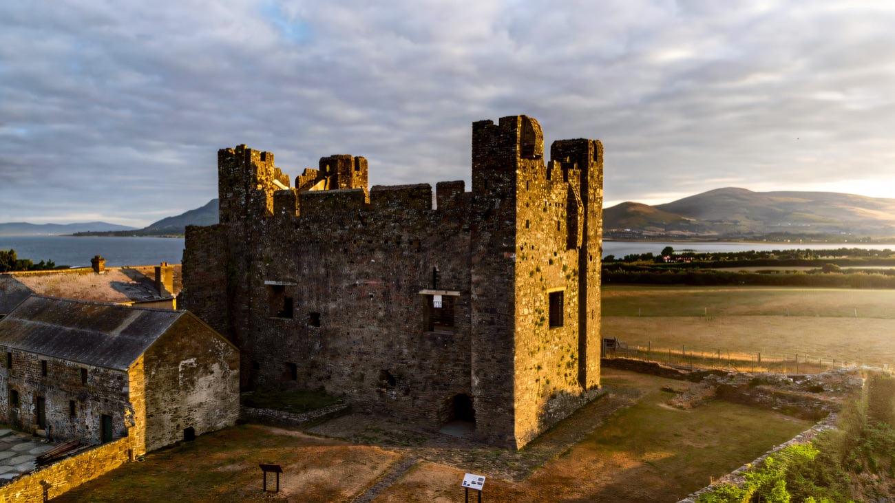 The great keep of Greencastle Royal Castle at golden hour, with Carlingford Lough and the Cooley mountains behind