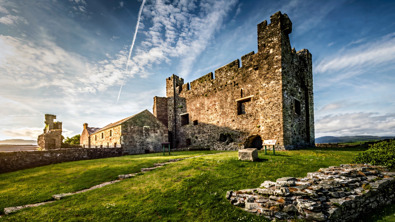 Greencastle's keep with its corner tower, curtain wall and grass sward under a blue sky