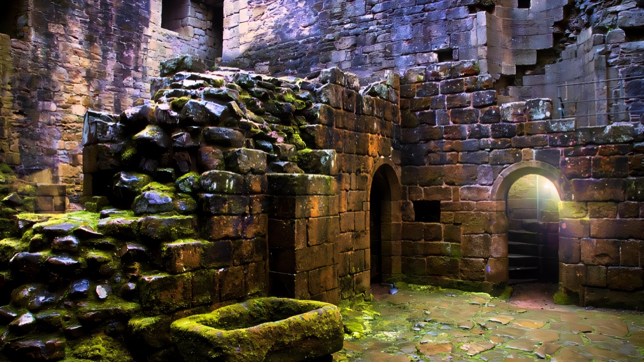 Inside the ruined keep of Greencastle — mossy stone walls, arched doorways and a flagstone floor