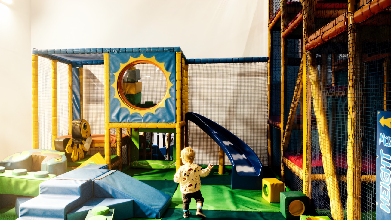 Toddler soft play zone with foam steps, a blue slide and a smiling bee character