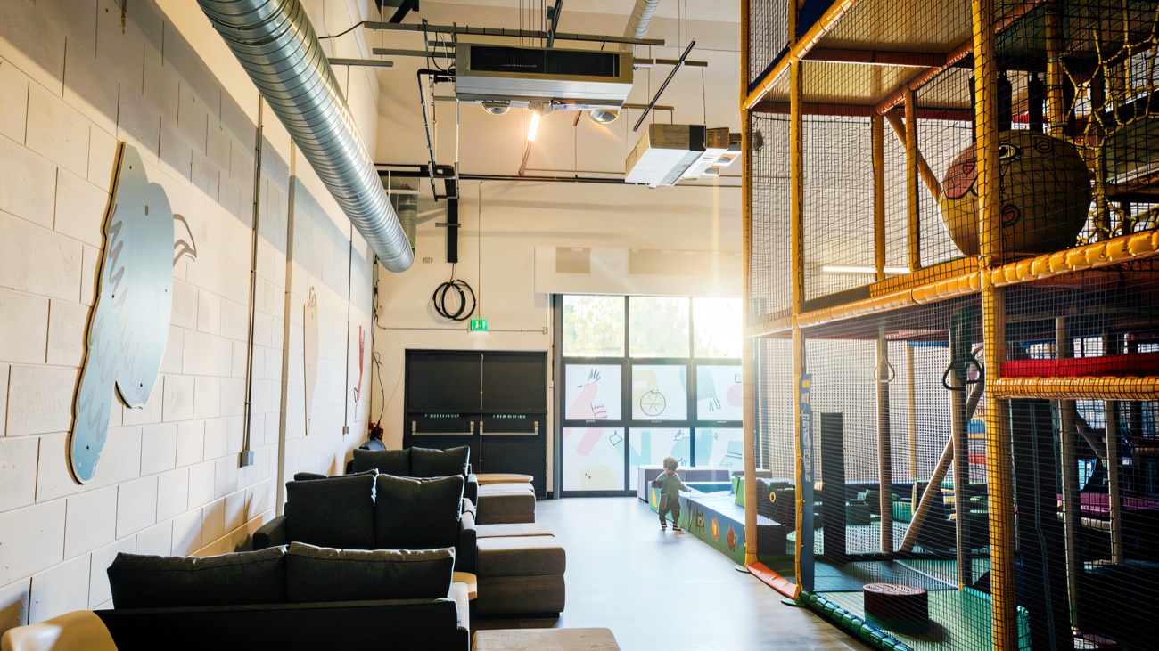 Bright open interior with sofa seating along the wall and the tall play frame on the right