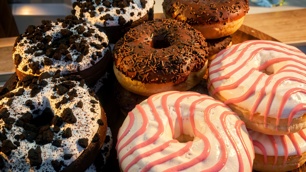 Iced doughnuts on a wooden board at the café counter