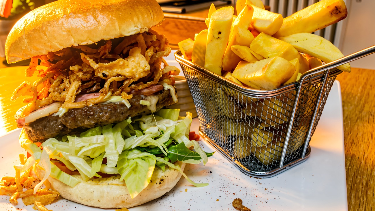 Burger with crispy onions served with a basket of chips