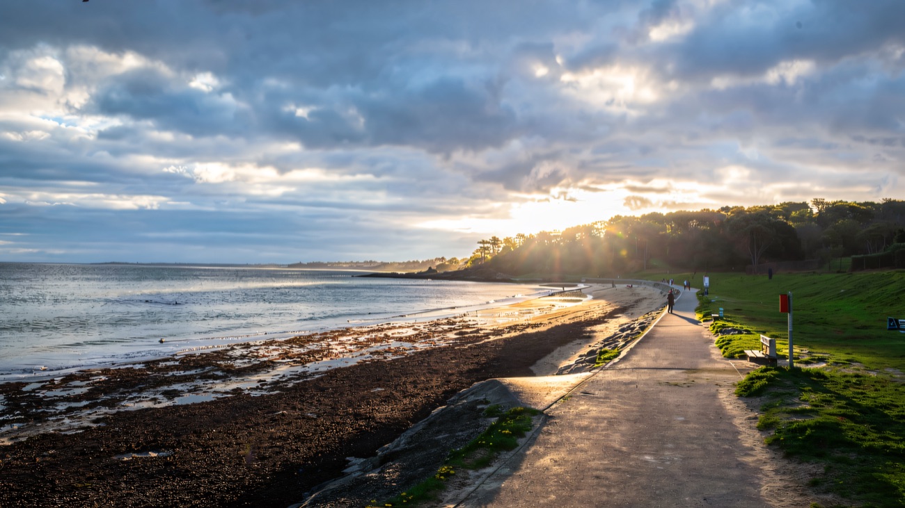 The coastal path hugs the shoreline beside the beach toward Bangor