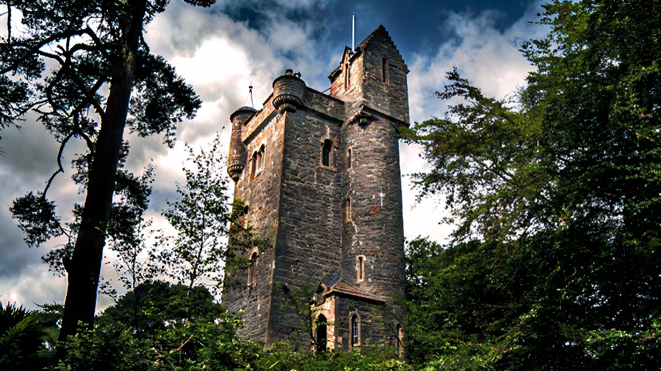 Helen's Tower seen from below through the estate trees against a blue sky