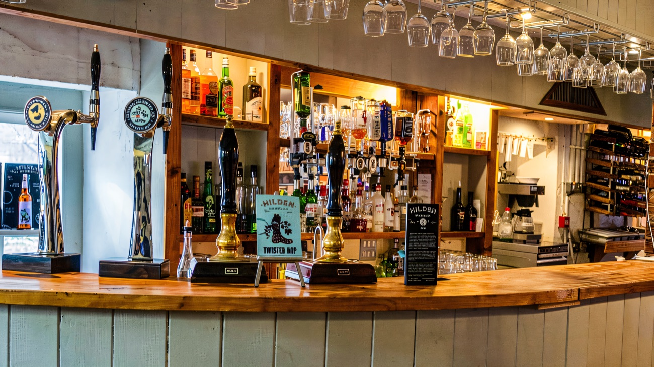 The curved wooden bar with rows of glasses hanging on racks above it