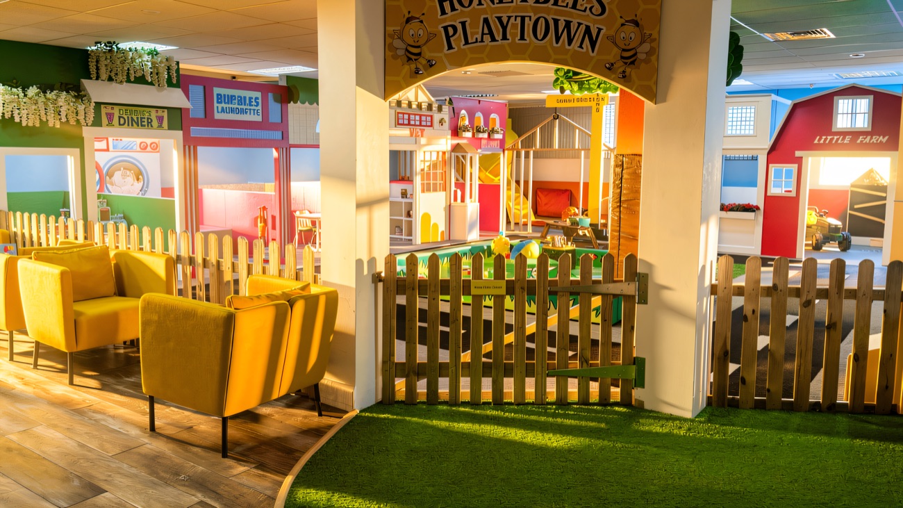 The Honeybees Playtown archway and picket gate, with soft yellow armchairs for grown-ups alongside