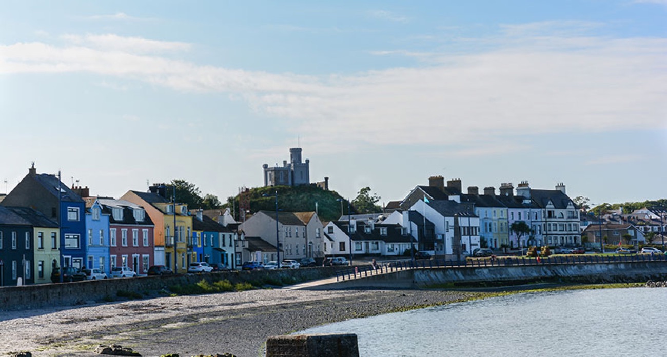 Donaghadee seafront with a row of colourful terraced houses and the Moat tower on the hill behind