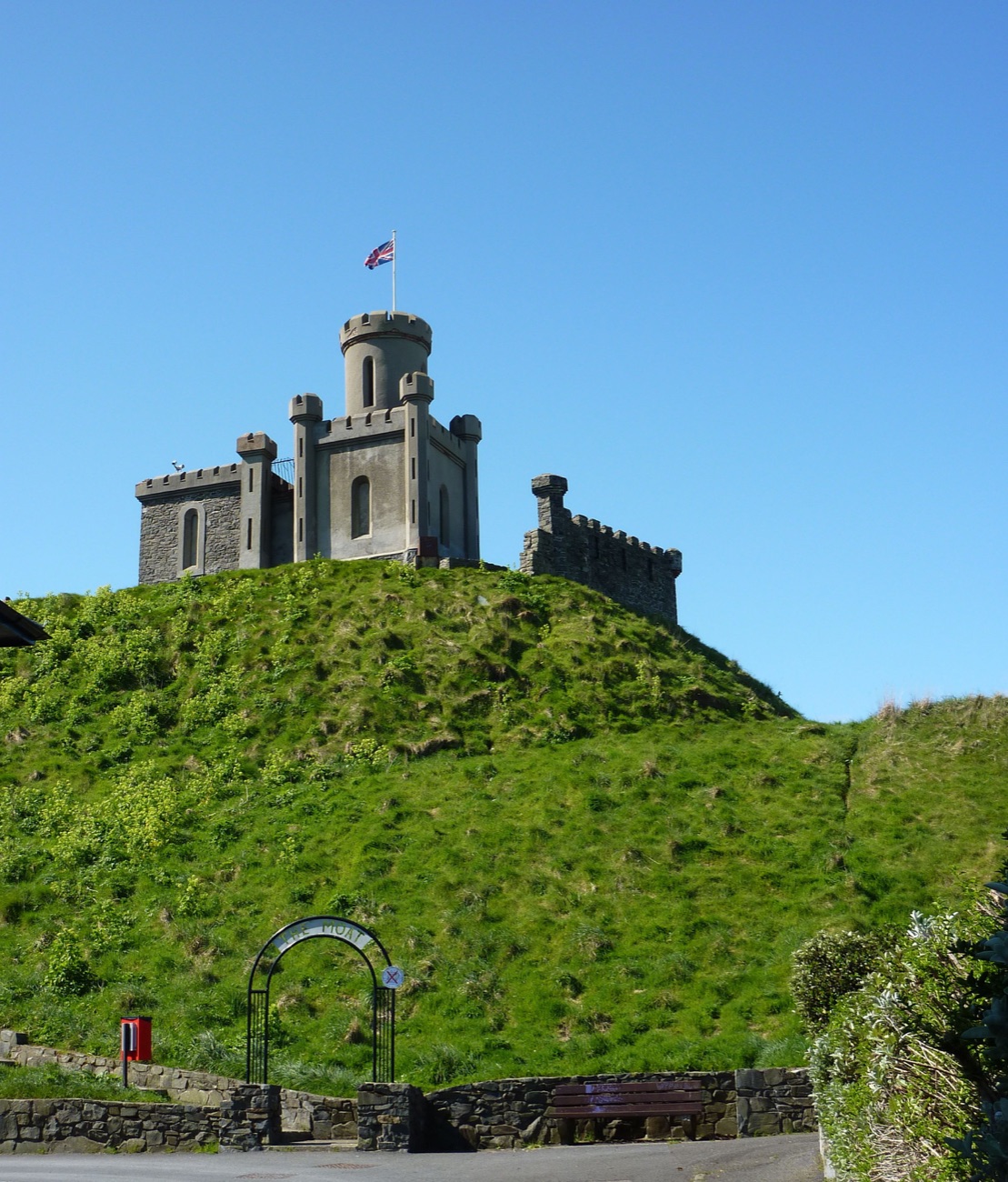 The Moat, Donaghadee's castellated stone tower standing on a grassy mound against a clear blue sky
