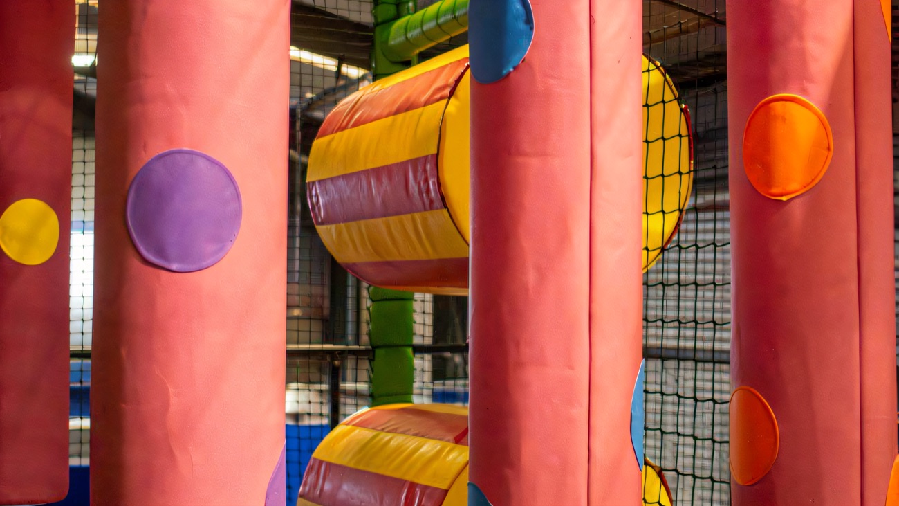 Padded polka-dot soft-play columns and rollers inside the netted junior play frame
