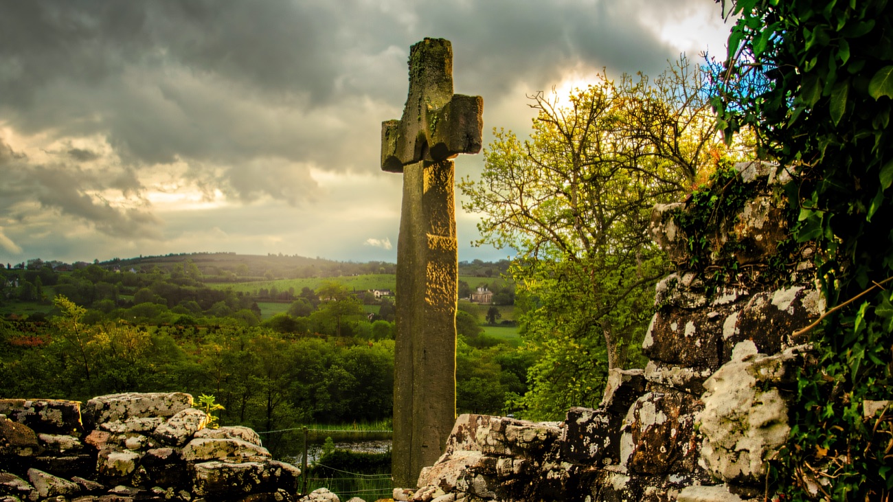 The cross framed by trees, with Lough Erne spread out beyond.
