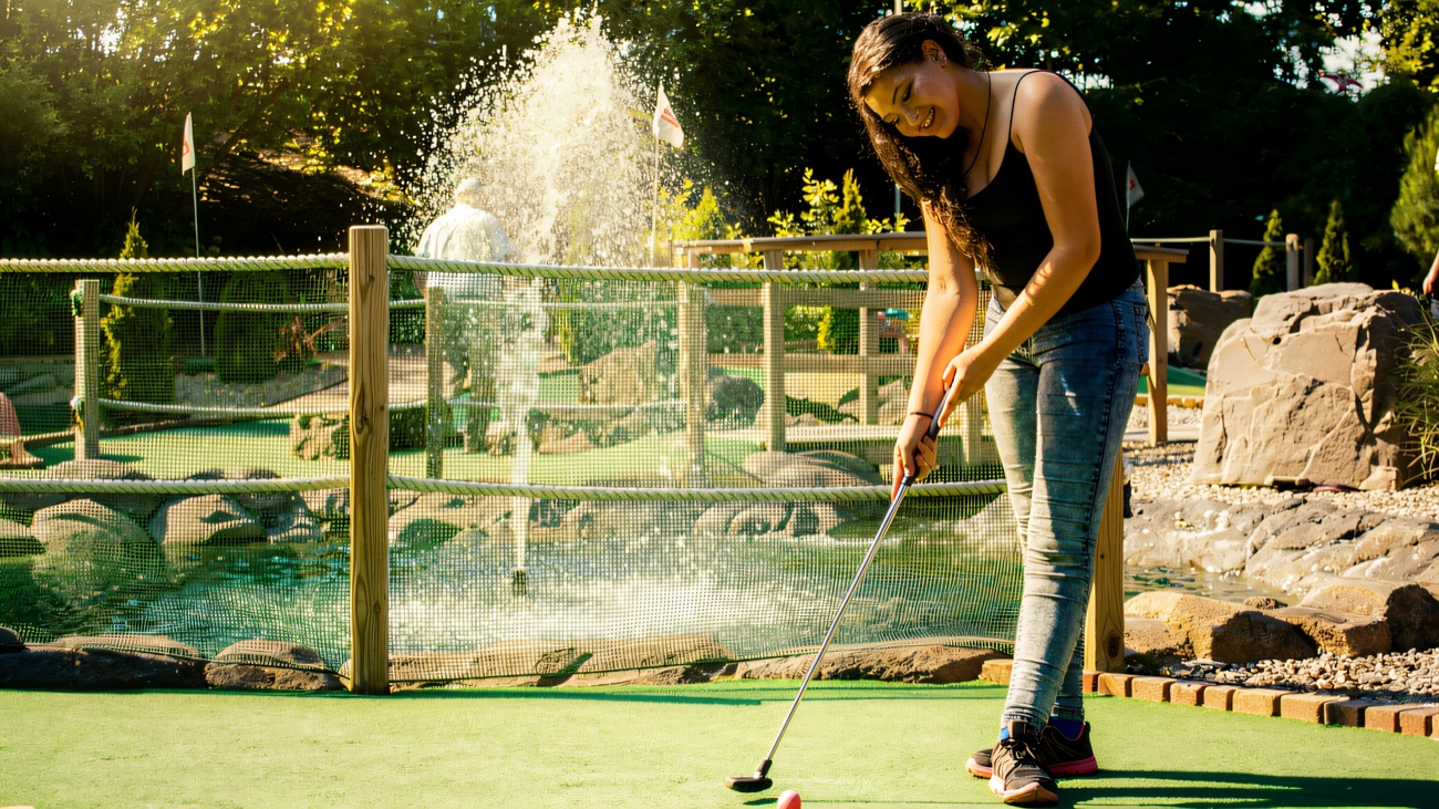 Lining up a putt beside the water feature on a sunny afternoon