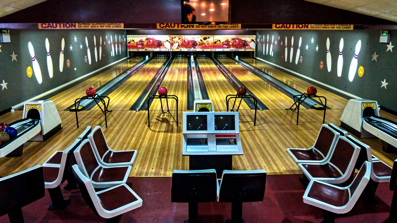 A front-on view of the bowling lanes with ball racks and moulded seating booths