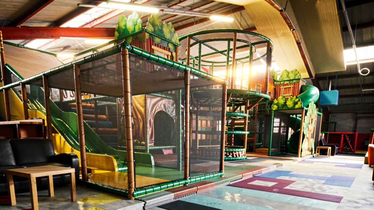 The jungle-themed play frame with a green wavy slide and climbing nets, with sofas set out alongside