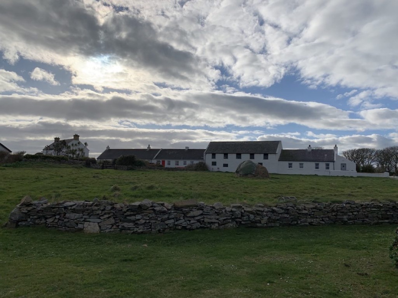 A drystone wall in front of the whitewashed cottages of Kearney hamlet under a big sky