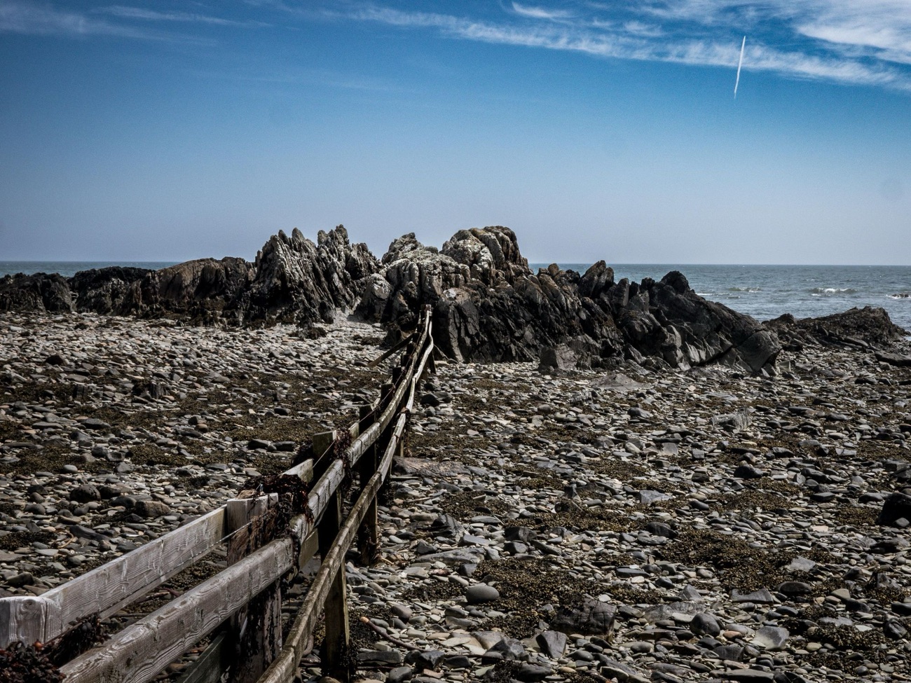 Lichen-covered slaty rocks and an old fence line running down to the sea on the Kearney coast