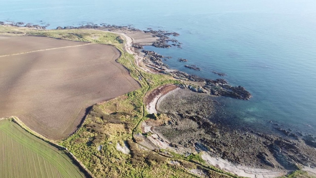 Aerial view of the rocky Kearney coast with the coastal path threading between the fields and the sea