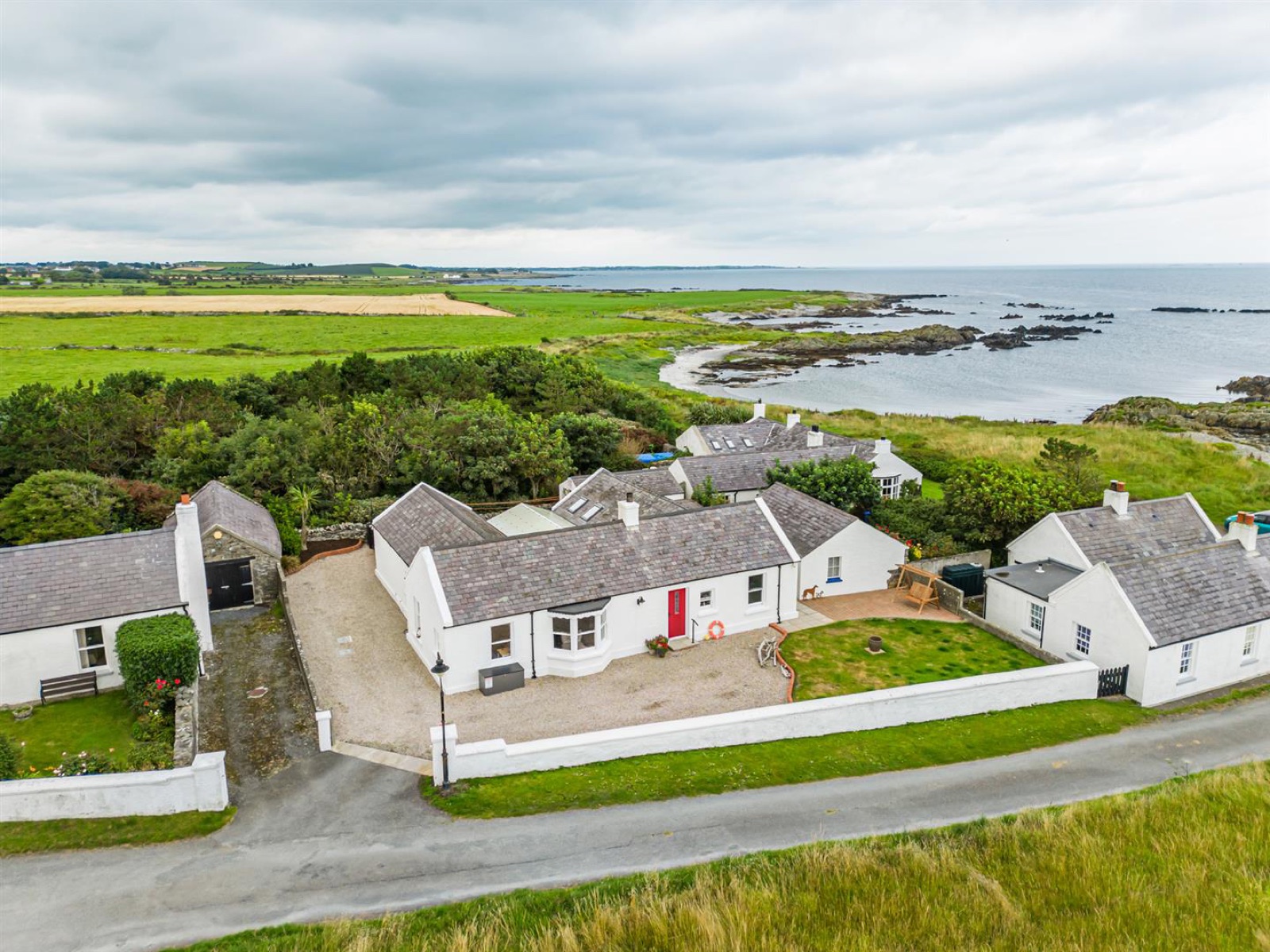 Whitewashed National Trust cottages at Kearney set on green fields beside the rocky sea coast near Portaferry
