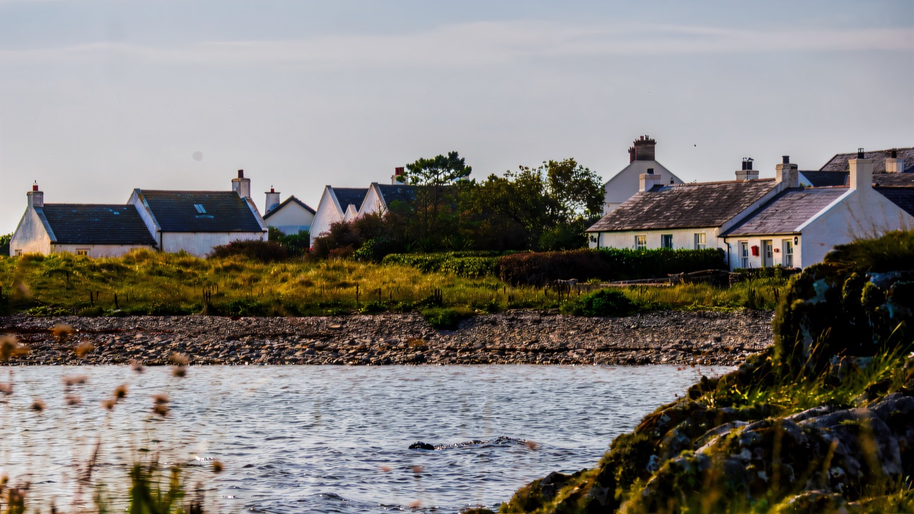 The whitewashed cottages of Kearney seen across the rocky Ards shore