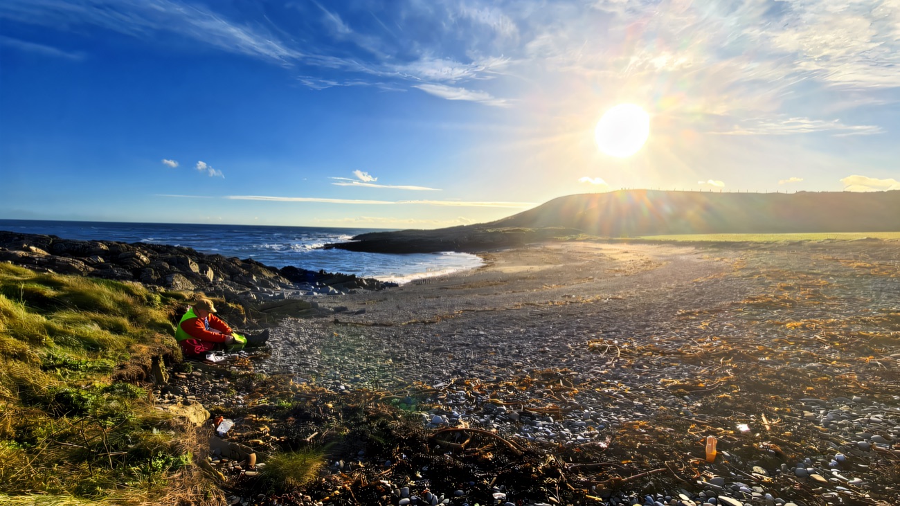 Low sun over a shingle cove, the headland catching the last light