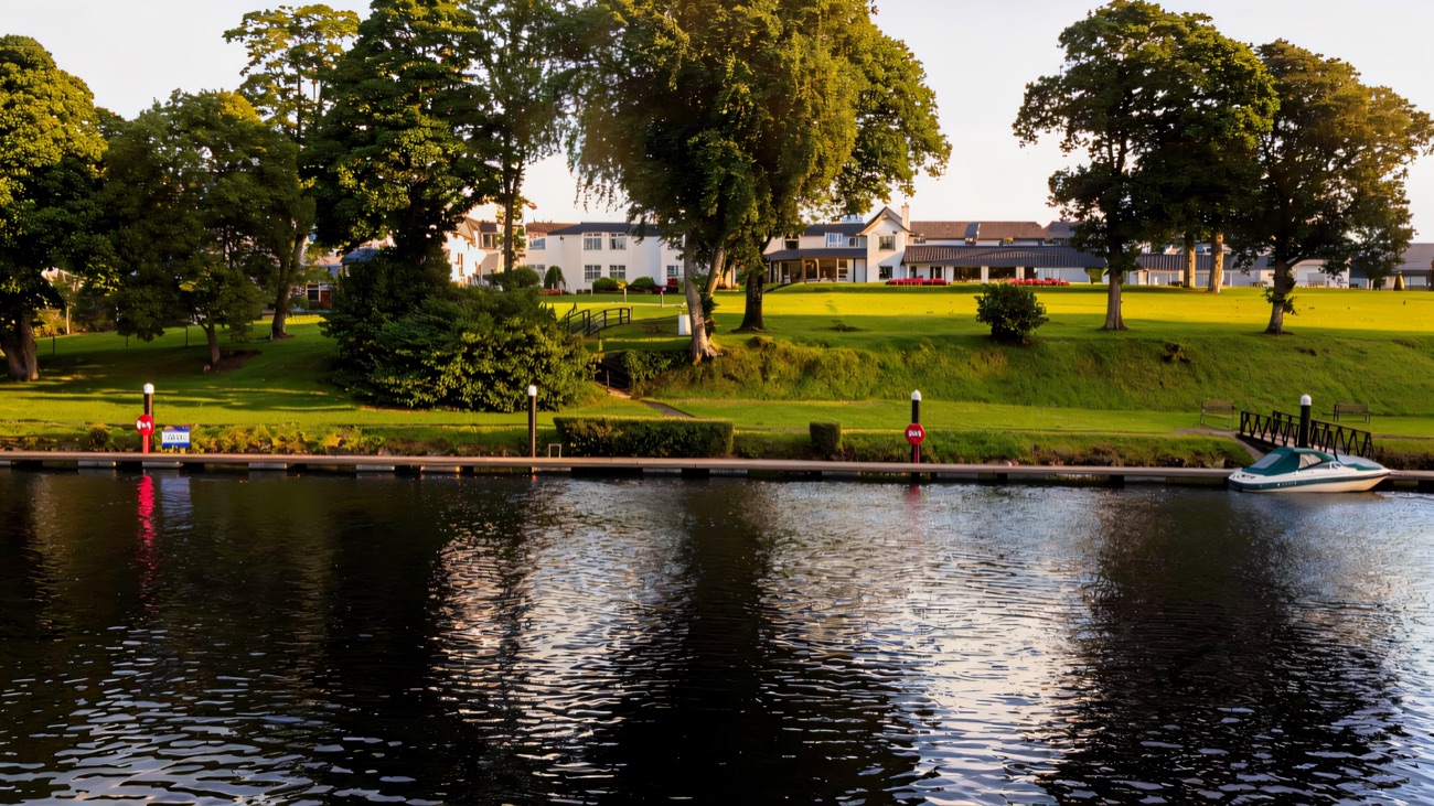 The hotel seen from across Lough Erne, with the marina jetty and a moored boat on the calm water