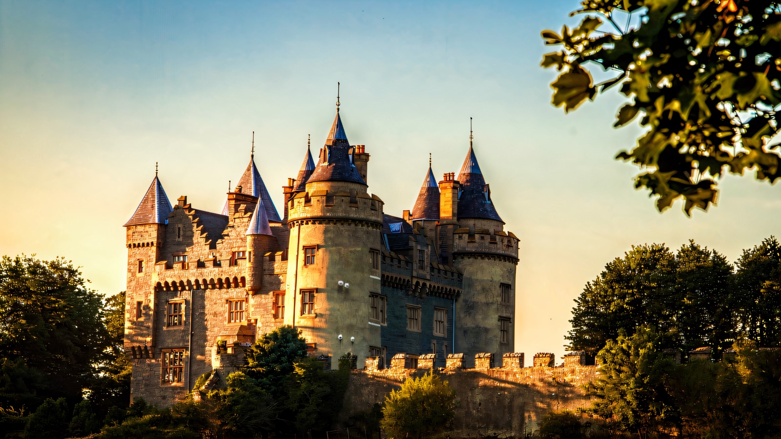 The turrets and blue-coned towers of Killyleagh Castle rising above the trees at golden hour